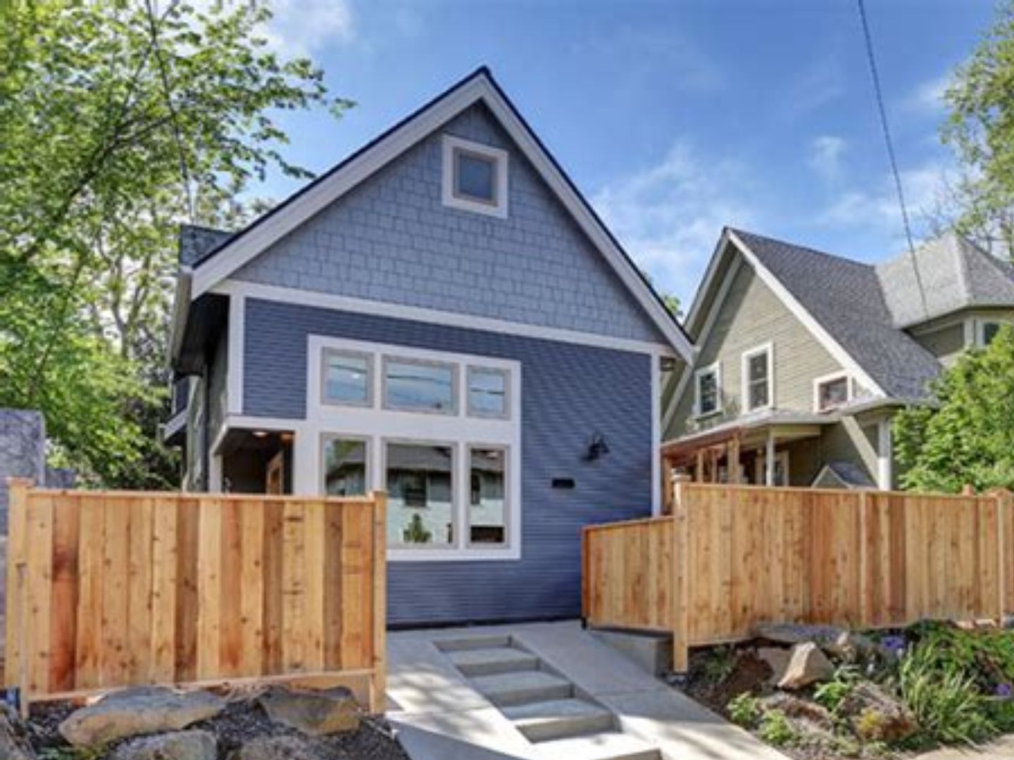 Completed detached ADU with blue shingle siding and cedar fence in California neighborhood