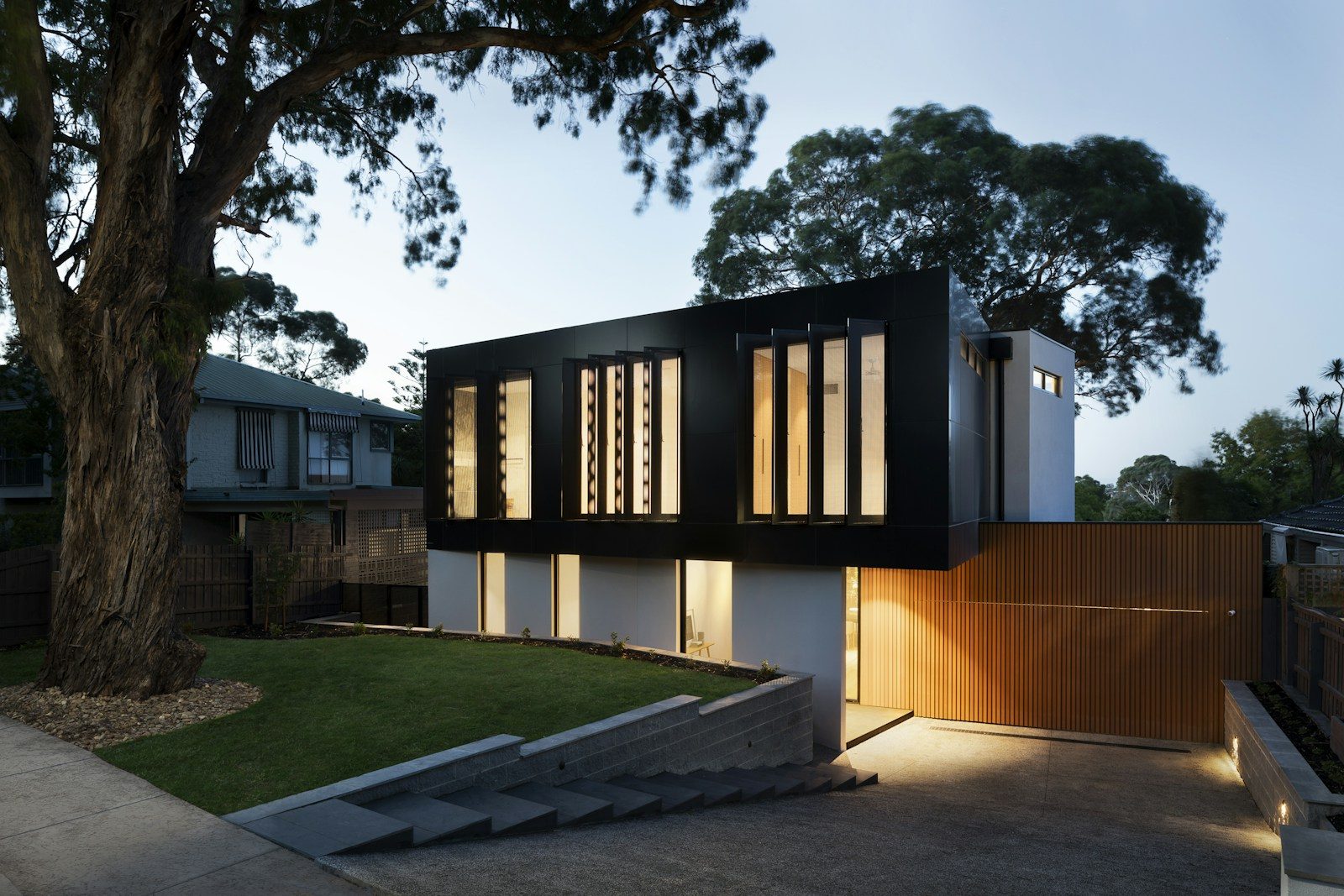 Modern accessory dwelling unit with dark cladding and warm interior lighting at night
